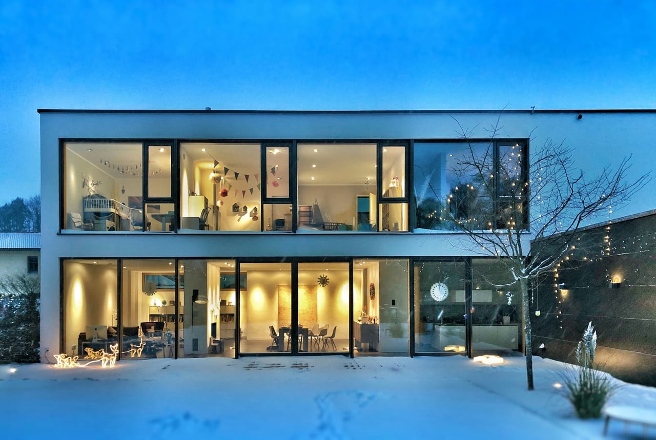 Modernes Haus am Abend mit erleuchteten Fensterfronten